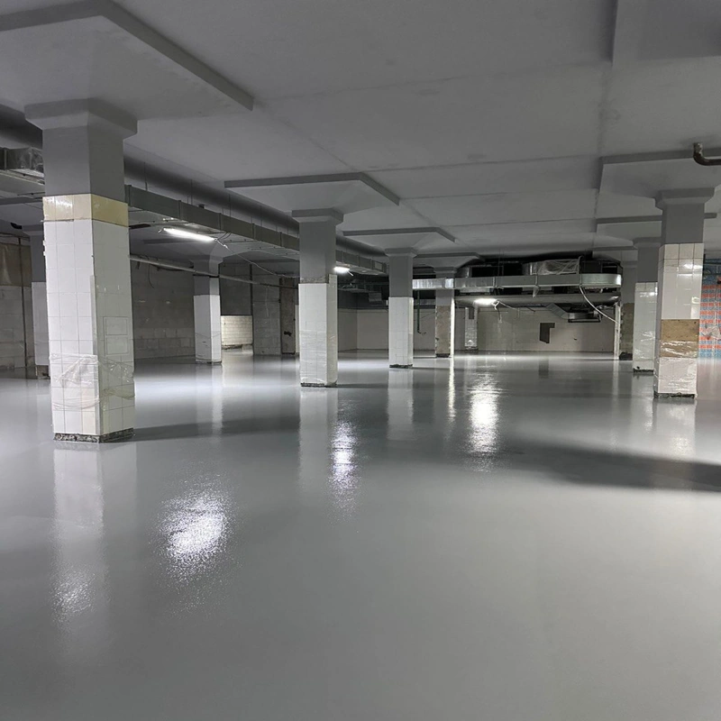 Glossy grey self-leveling epoxy floor in a large industrial space with pillars.