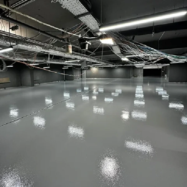 High-gloss grey epoxy floor in a large commercial space with exposed ceiling.