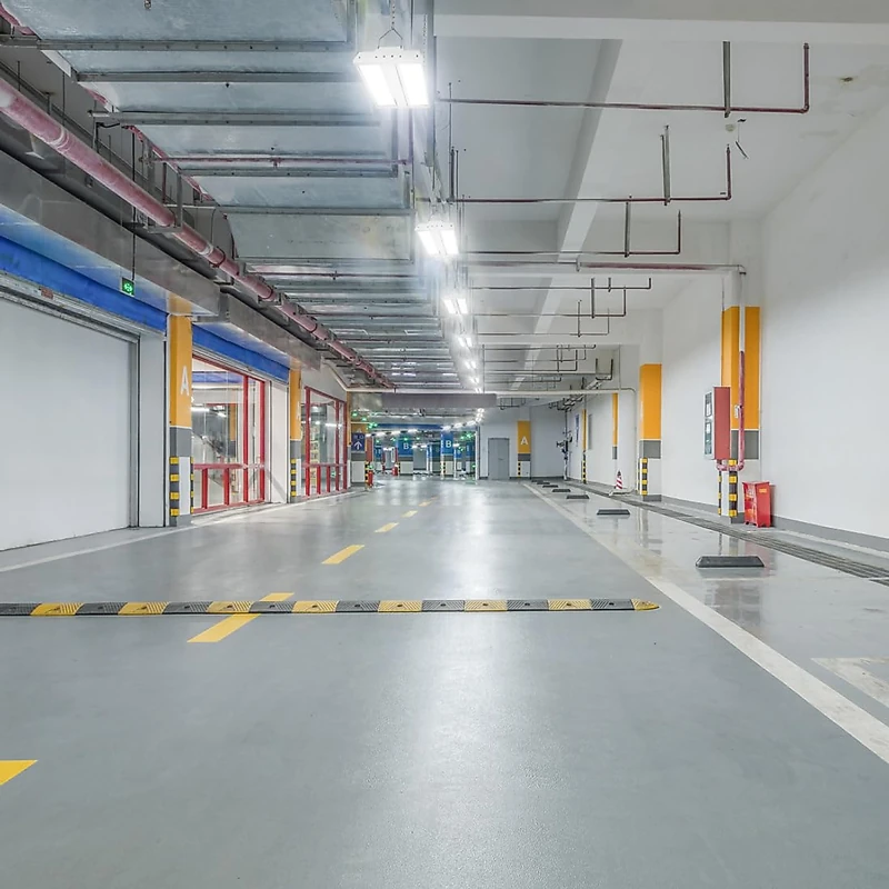 Seamless grey self-leveling epoxy floor in a modern underground parking garage.