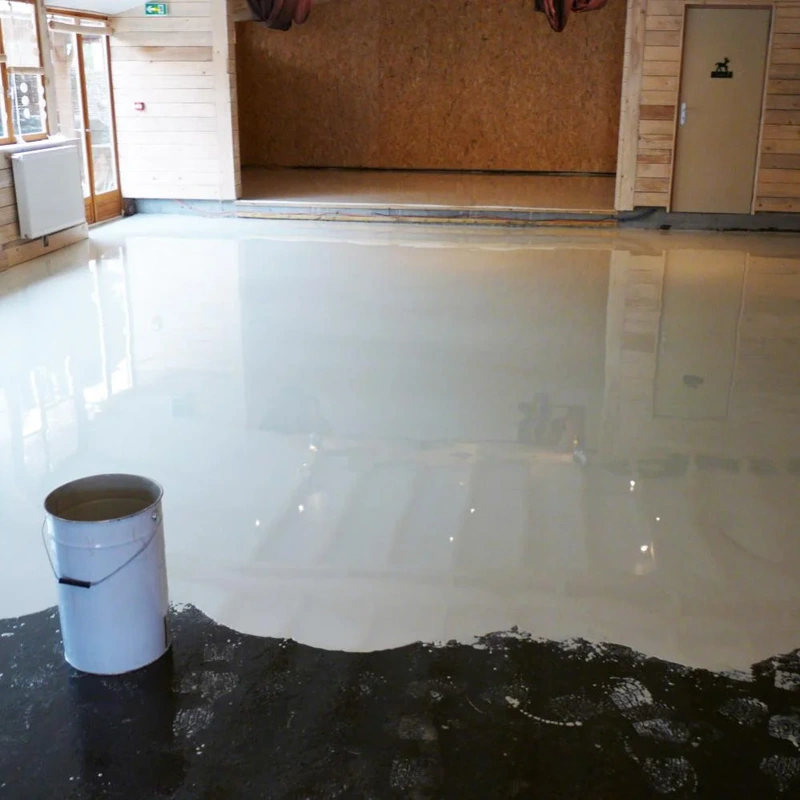 Smooth white self-leveling epoxy flooring being poured in a studio space.