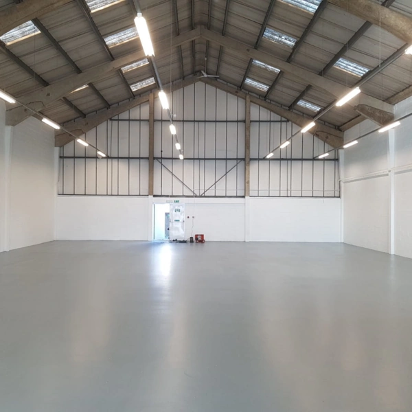 Spacious empty industrial unit featuring a smooth, matte gray epoxy floor