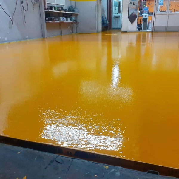 Vibrant yellow high-gloss epoxy flooring in an industrial workshop setting.